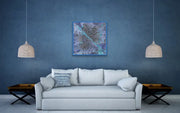 Framed Milky Way Galaxy hanging on white wall In room with light grey couch, 2 ceiling lamps, 2 side tables